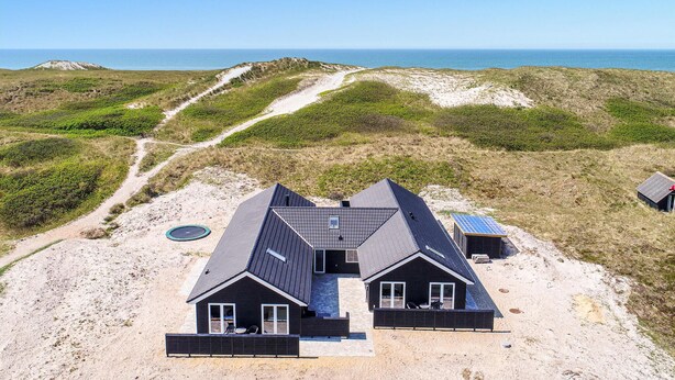 A modern house with a sloped roof, large windows, and a patio area. - Stunning home in Hvide Sande with sauna (Hvide Sande)