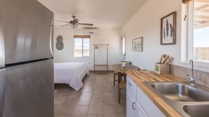 A compact kitchen with a refrigerator, wooden countertop, and a sink.