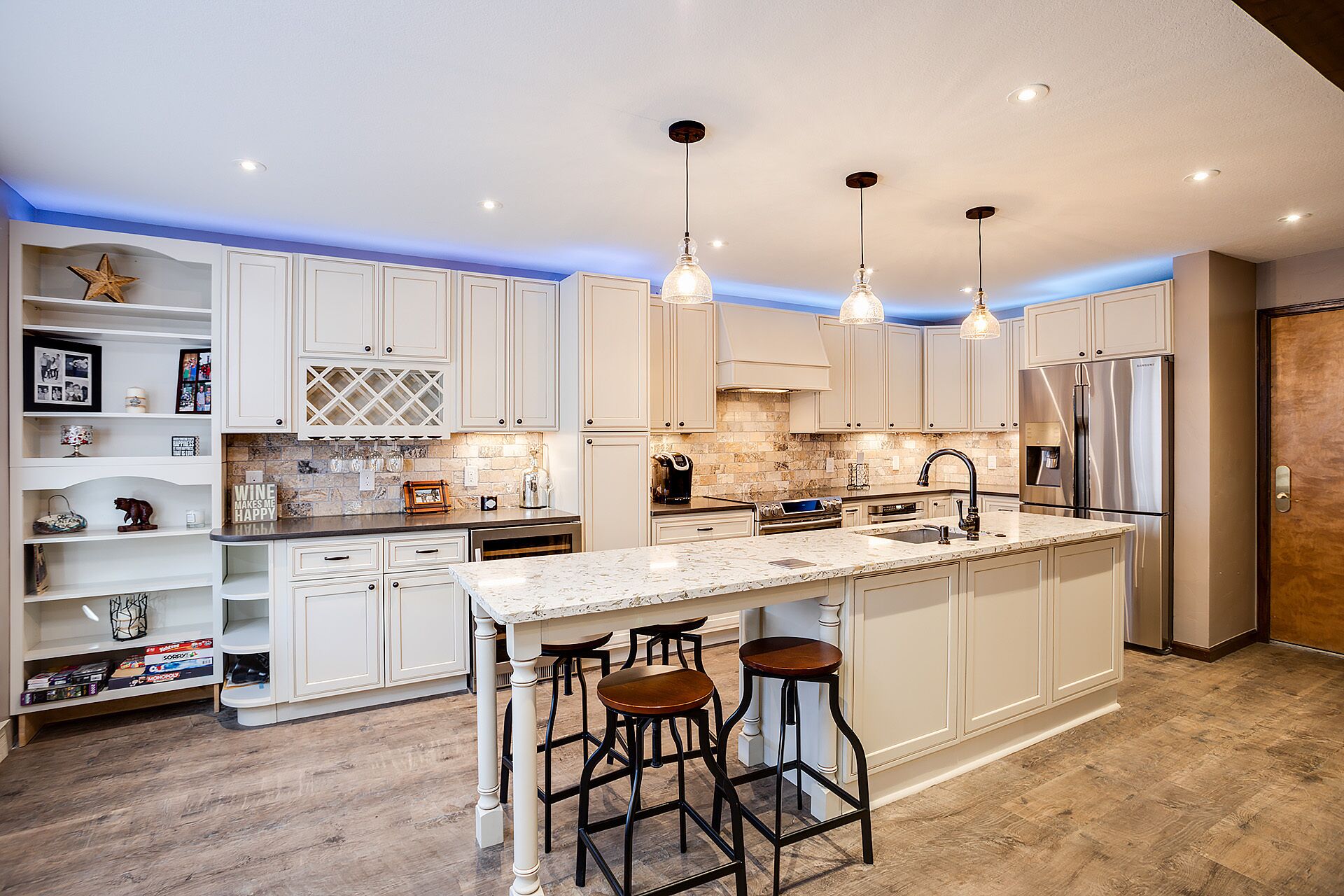 A modern kitchen with white cabinetry, a large island with bar stools, and pendant lighting.