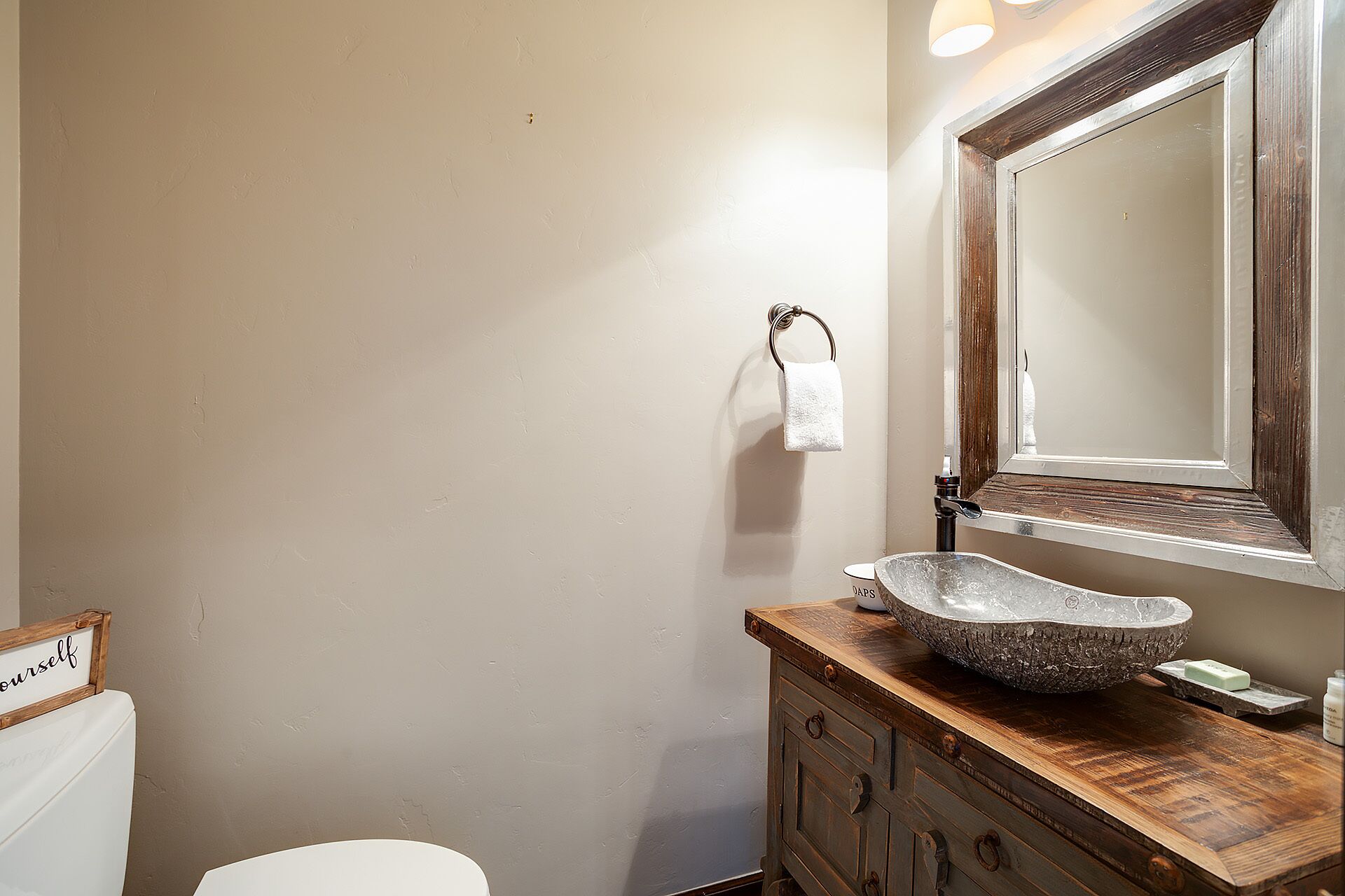 Une salle de bain avec un meuble-lavabo en bois, un grand miroir et des toilettes blanches.