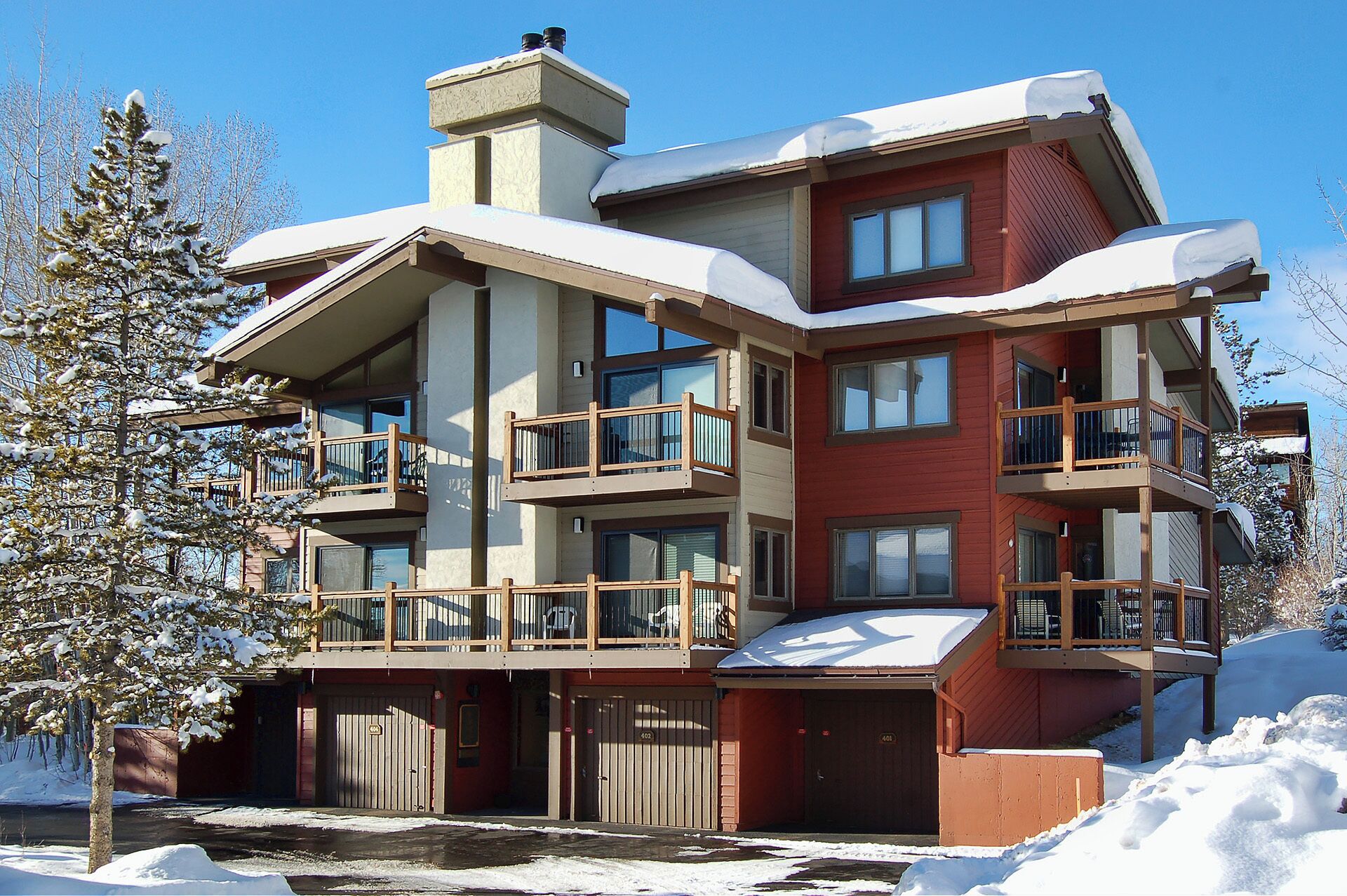 Un edificio de varios pisos con balcones, garaje y paisajes nevados.