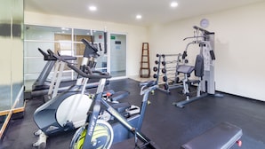 A gym with cardio equipment, weight machines, and a mirror.