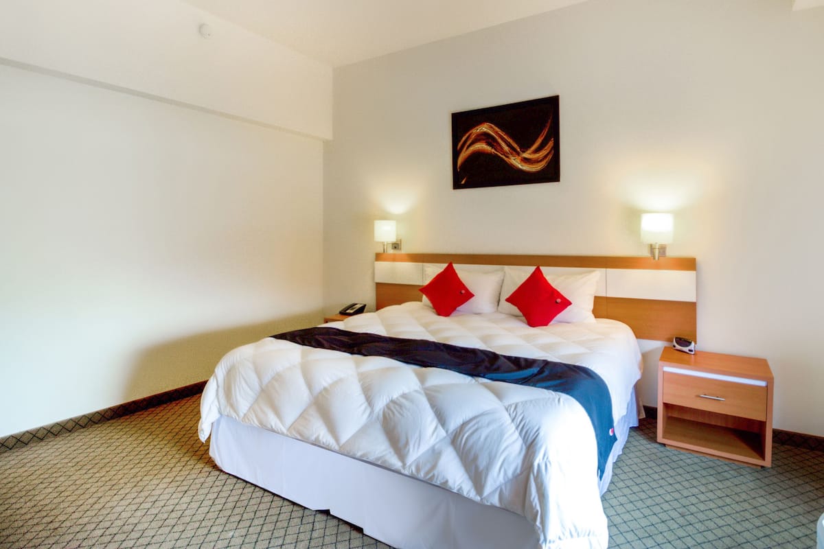 A hotel room with a bed, bedside tables, and a wall-mounted artwork.