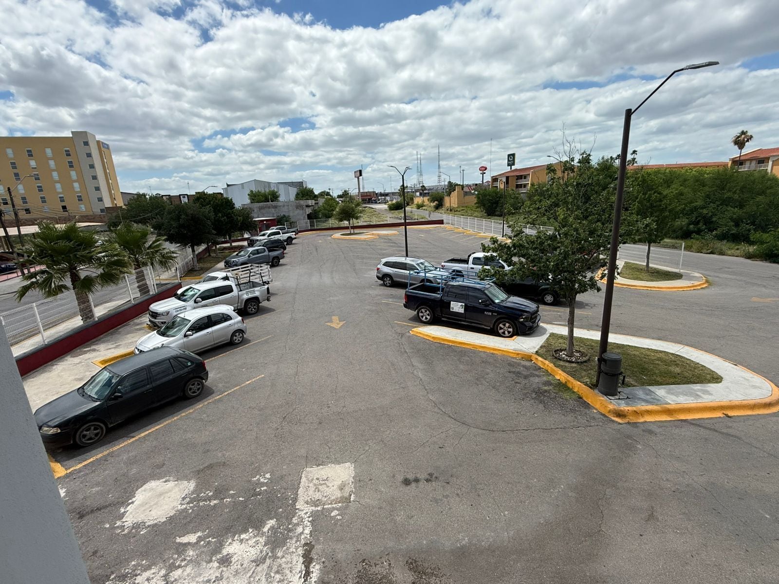 A parking lot with multiple cars, a building in the background, and a clear sky.