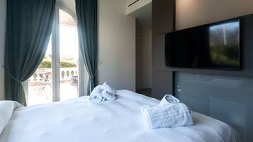 Habitación de hotel con una cama, un televisor montado en la pared y vistas al exterior a través de una ventana.