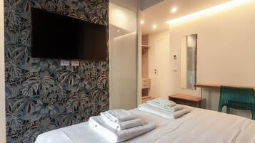 A hotel room with a bed, a TV mounted on the wall, a mirror, and a wardrobe.