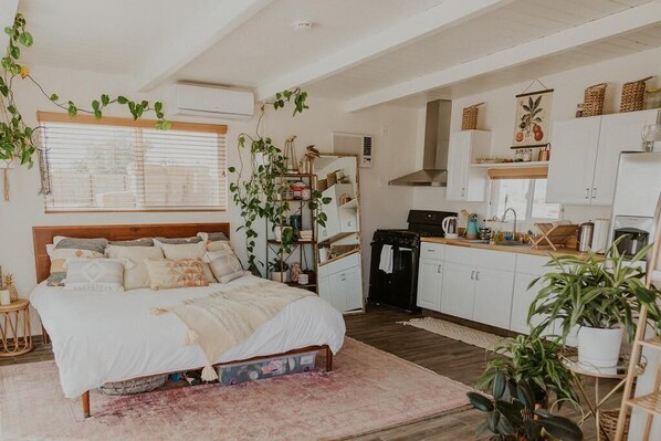 A bedroom with a bed, bedside tables, and a window with blinds. - Mesquite Cabin Studio w/ Private Hot Springs Tub (Twentynine Palms)