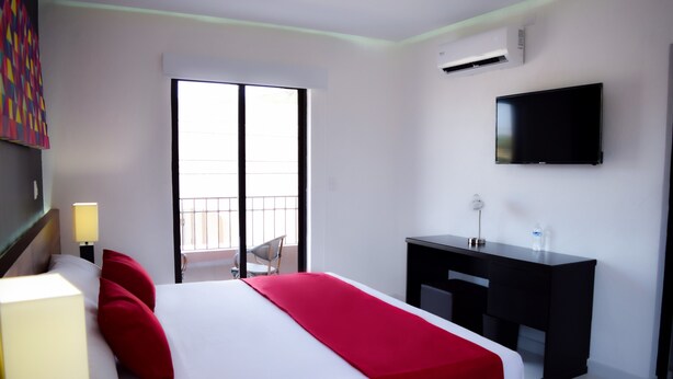 A hotel room with a bed, a desk, a TV, and a window. - Hotel Dwana (Mazatlán)