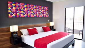 A modern hotel room with a large bed, two bedside tables with lamps, a colorful geometric wall art, and a view of the outside balcony. - Hotel Dwana (Mazatlán)