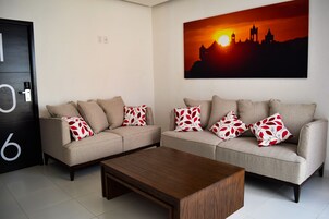 Una sala de estar con dos sofás, una mesa de centro y un cuadro de un horizonte al atardecer.