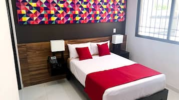 Une chambre d’hôtel moderne avec une grande œuvre d’art géométrique au mur, une tête de lit en bois, un lit avec une literie blanche et rouge, des lampes de chevet et une table de chevet avec un téléphone.
