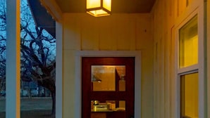 Une véranda en bois avec une table et des chaises, un luminaire suspendu et une porte dotée d’une fenêtre.