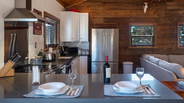 Une cuisine moderne avec des meubles blancs, un réfrigérateur en acier inoxydable et un coin repas avec une table dressée pour deux personnes.