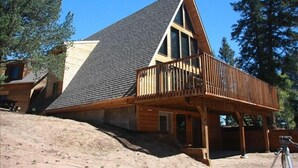 A wooden cabin with a sloped roof, a balcony, and a small porch area.