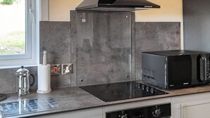Eine Küche mit einer schwarzen Mikrowelle, einem Herd und einer Kaffeemaschine auf der Arbeitsplatte.