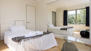 A hotel room with two beds, a large mirror, a glass table, and a view of trees through the window. - Hilltop Getaway - Superb Sea & Mountain Views with Spa pool! (Nelson)