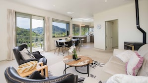 A spacious living area with a balcony, a dining area, and a kitchen. - Hilltop Getaway - Superb Sea & Mountain Views with Spa pool! (Nelson)