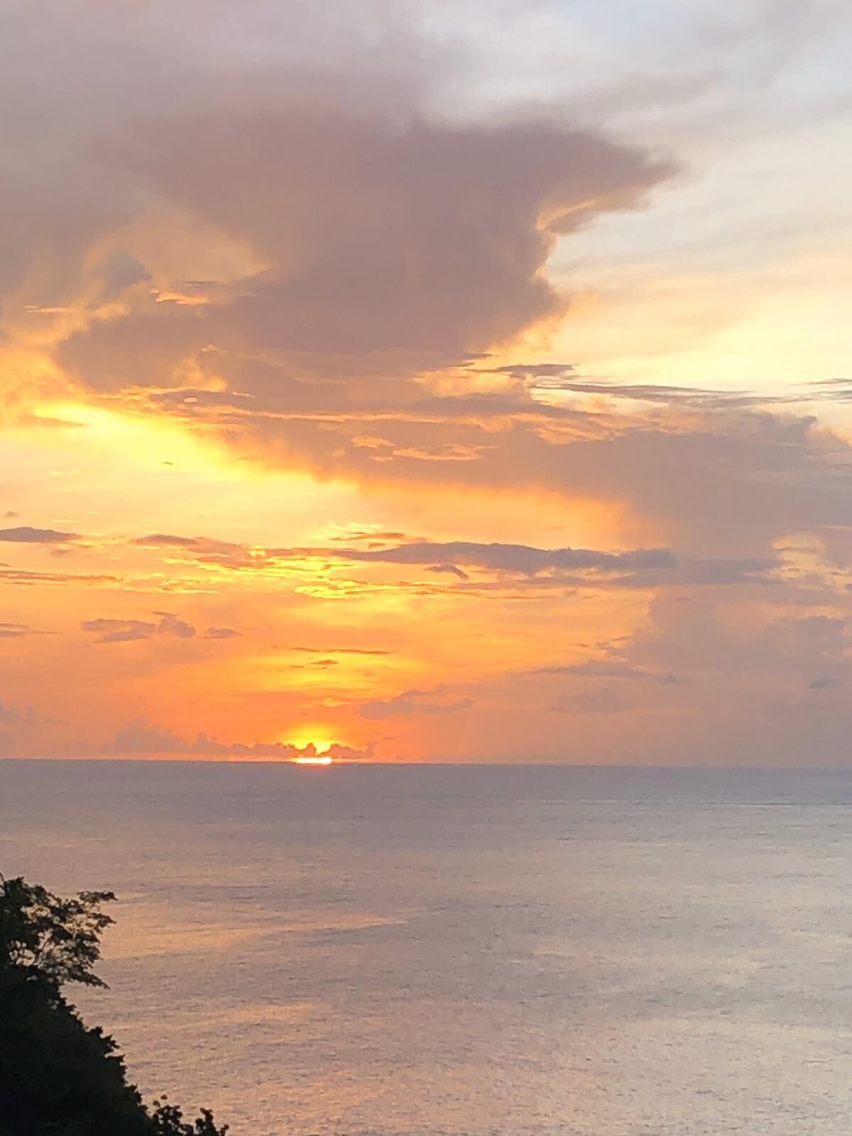 A sunset over a calm sea with a clear horizon.