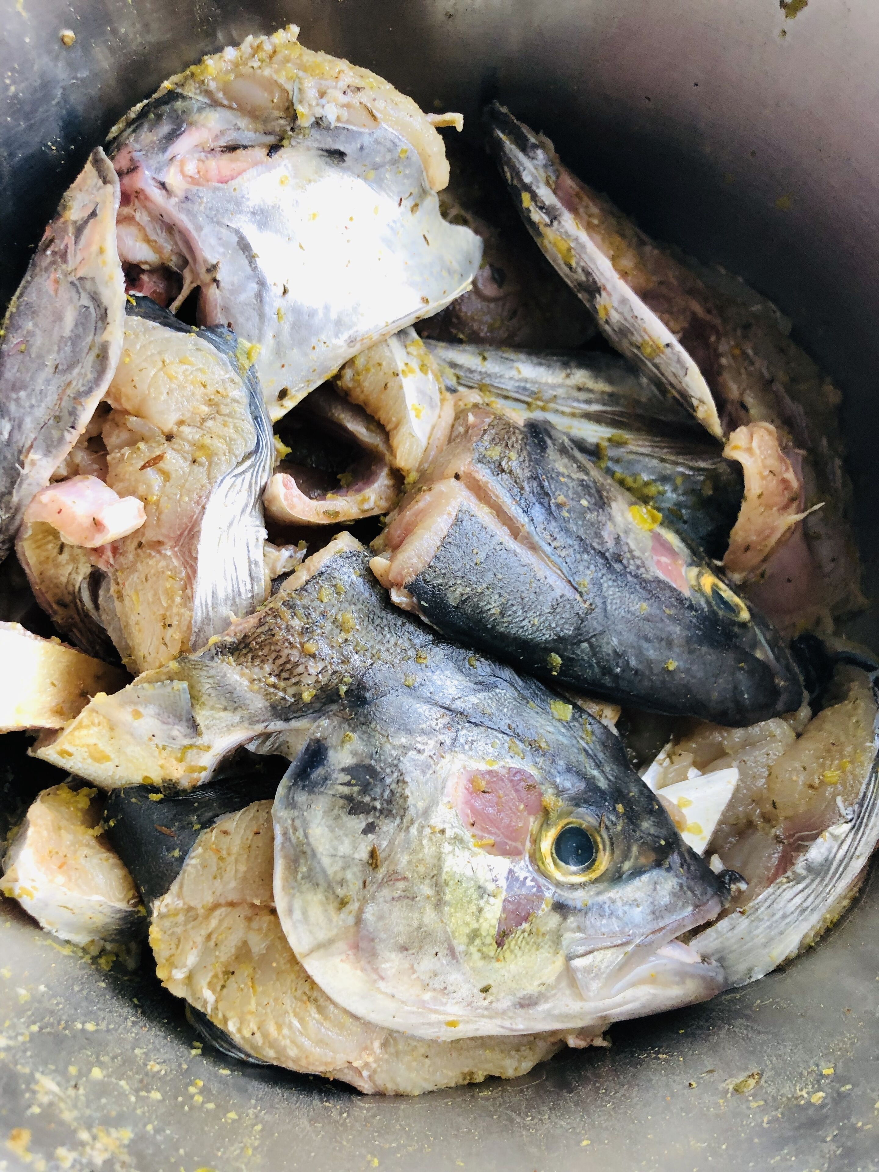A metal container filled with raw fish, some of which are gutted.