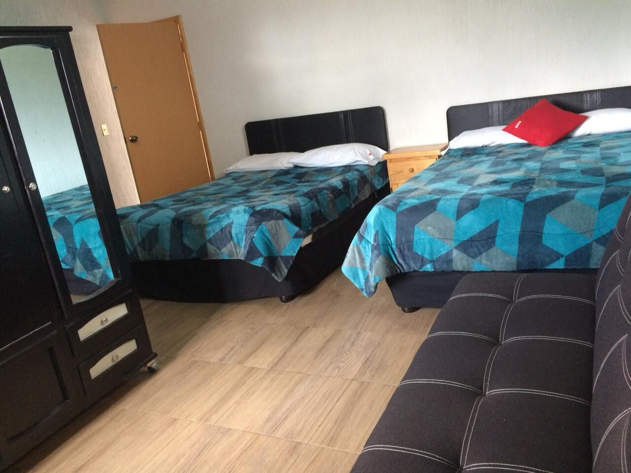 Una habitación con dos camas, un armario y un sofá.