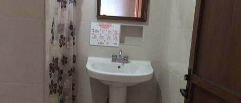 A small bathroom with a white sink, a mirror above it, and a shower curtain with a floral pattern.
