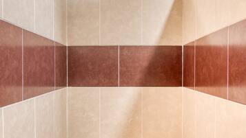 A small, narrow bathroom with beige and brown tiles, a white toilet, and a small shelf.