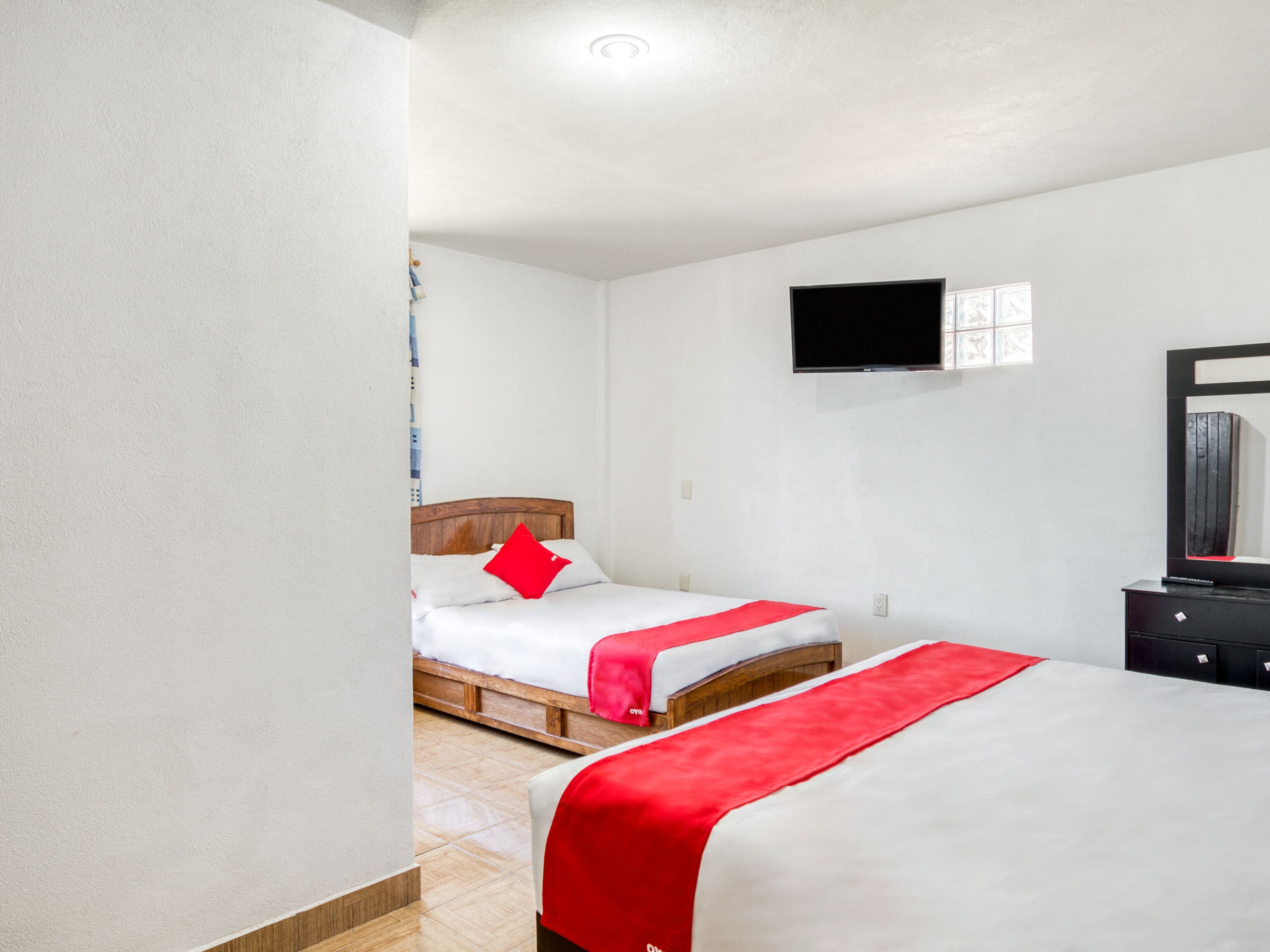 Ein Hotelzimmer mit zwei Betten, einem flachbildfernseher an der Wand und einem Schminktisch.