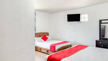 Ein Hotelzimmer mit zwei Betten, einem flachbildfernseher an der Wand und einem Schminktisch.