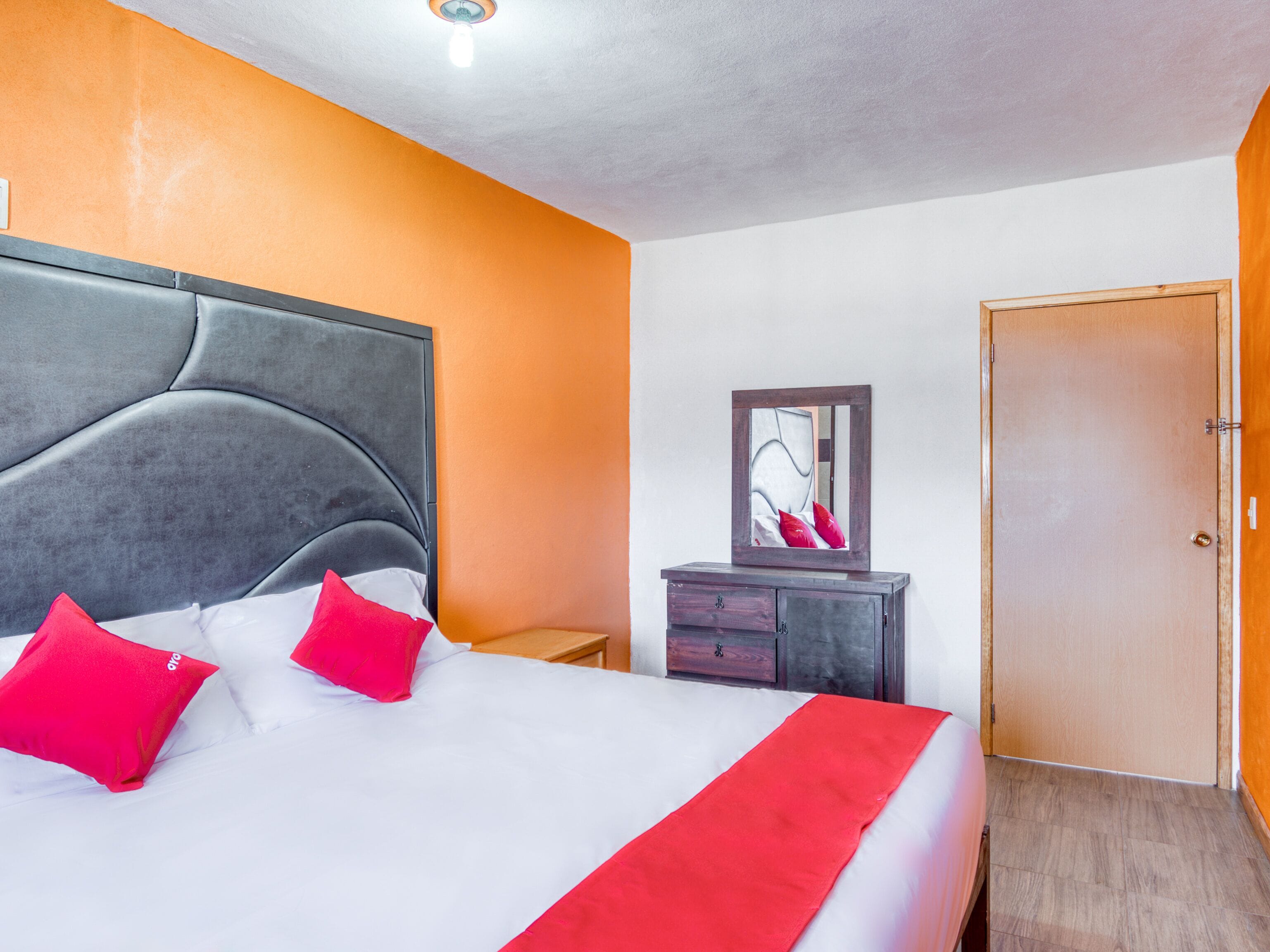 Una habitación de hotel con una cama grande, un aparador, un espejo y una puerta.