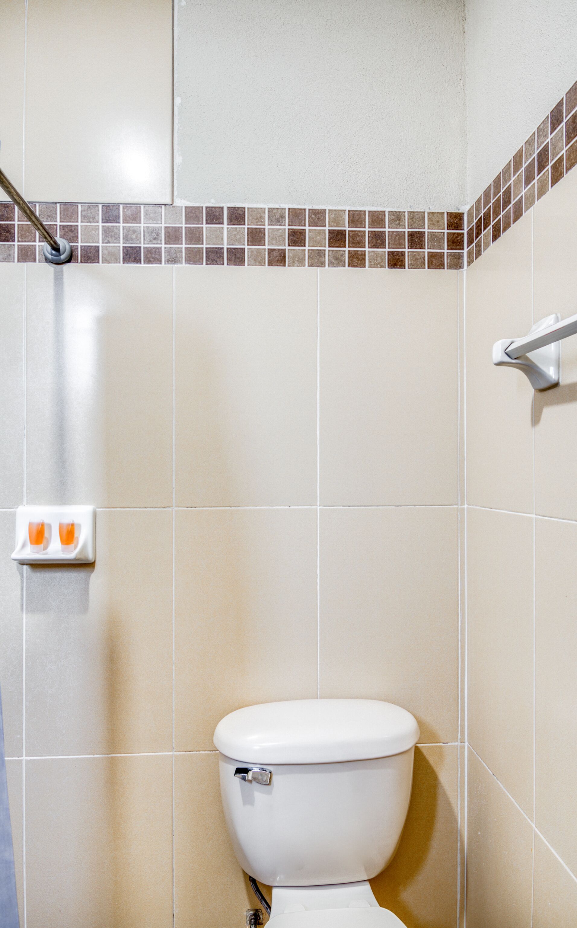 A bathroom with a toilet, a shower, and a hand dryer.