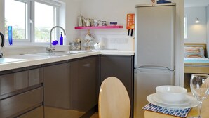 A modern kitchen with a built-in dishwasher, a sink with a faucet, and a window. - 2 bedroom accommodation in Chideock (Chideock)
