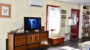 Uma sala de estar com um armário de madeira, uma televisão, uma bicicleta e uma estante de livros.