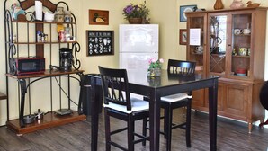 Uma cozinha com mesa de jantar, cadeiras, geladeira, cafeteira e armário com portas de vidro.