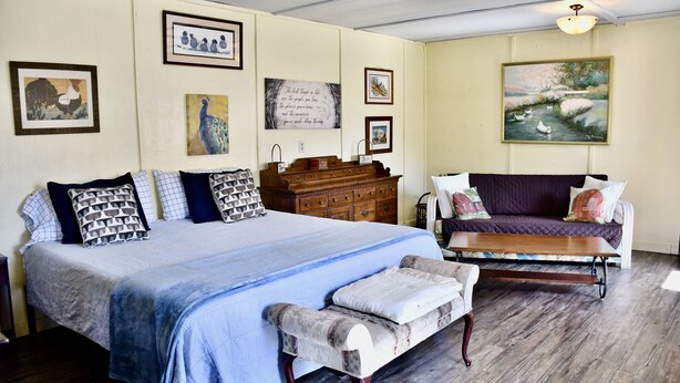 Quarto com uma cama grande, cómoda de madeira, sofá e um banquinho.