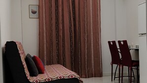 Ein Zimmer mit einer Couch, einem Esstisch mit Stühlen und einer Deckenleuchte.