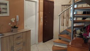 Ein Flur mit einem Holzkabinett, einer Tür und einer Wendeltreppe.