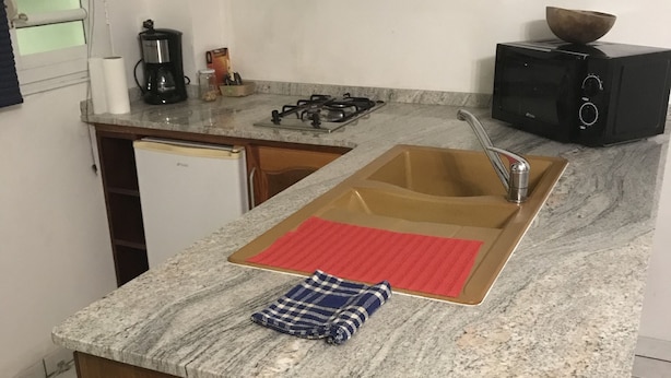 Una cocina con encimera de granito, un fregadero, una estufa y un microondas.