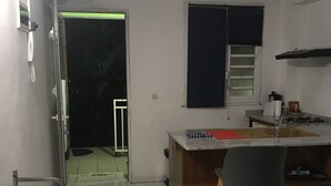 Cocina con un lavamanos, estufa y una silla. Hay una puerta que da a otra habitación.