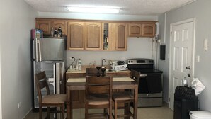 Una cucina compatta con mobili in legno, un frigorifero, un fornello e un tavolo da pranzo con sedie.