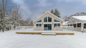 Ein zweistöckiges Haus mit weißem Deck und überdachter Veranda.