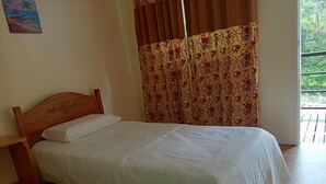 A single bed with a wooden headboard, white bedding, and a floral curtain.