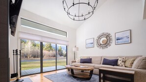 A modern living room with a large sliding glass door leading to a view of a grassy area and mountains. - RMR: Cinquefoil 1615 Condo in The Aspens/Wilson,WY (Wilson)