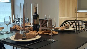 Een eettafel gedekt met wijnglazen, een fles en een doosje met de tekst 'HERZLICH WILSA'.