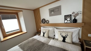 Een slaapkamer met een bed, een raam, een hoofdeinde en wanddecoraties.