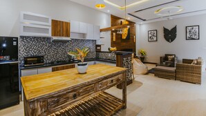 A modern kitchen with a wooden dining table, white cabinets, and a black tiled backsplash. - Rommy Villas Lembongan (Lembongan Island)