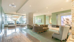 A spacious lobby with a high ceiling, a large seating area with sofas and armchairs, a reception desk, and a large screen displaying an image. - Sapphire , South Padre Island  Texas.<br> 6th floor ; Best Ocean View in SPI (South Padre Island)