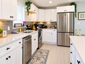 A modern kitchen with white cabinets, stainless steel appliances, and a decorative backsplash.