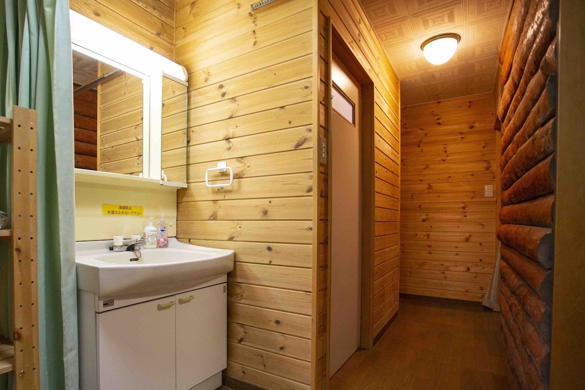 A wooden cabin-style bathroom with a sink, mirror, and wooden walls.