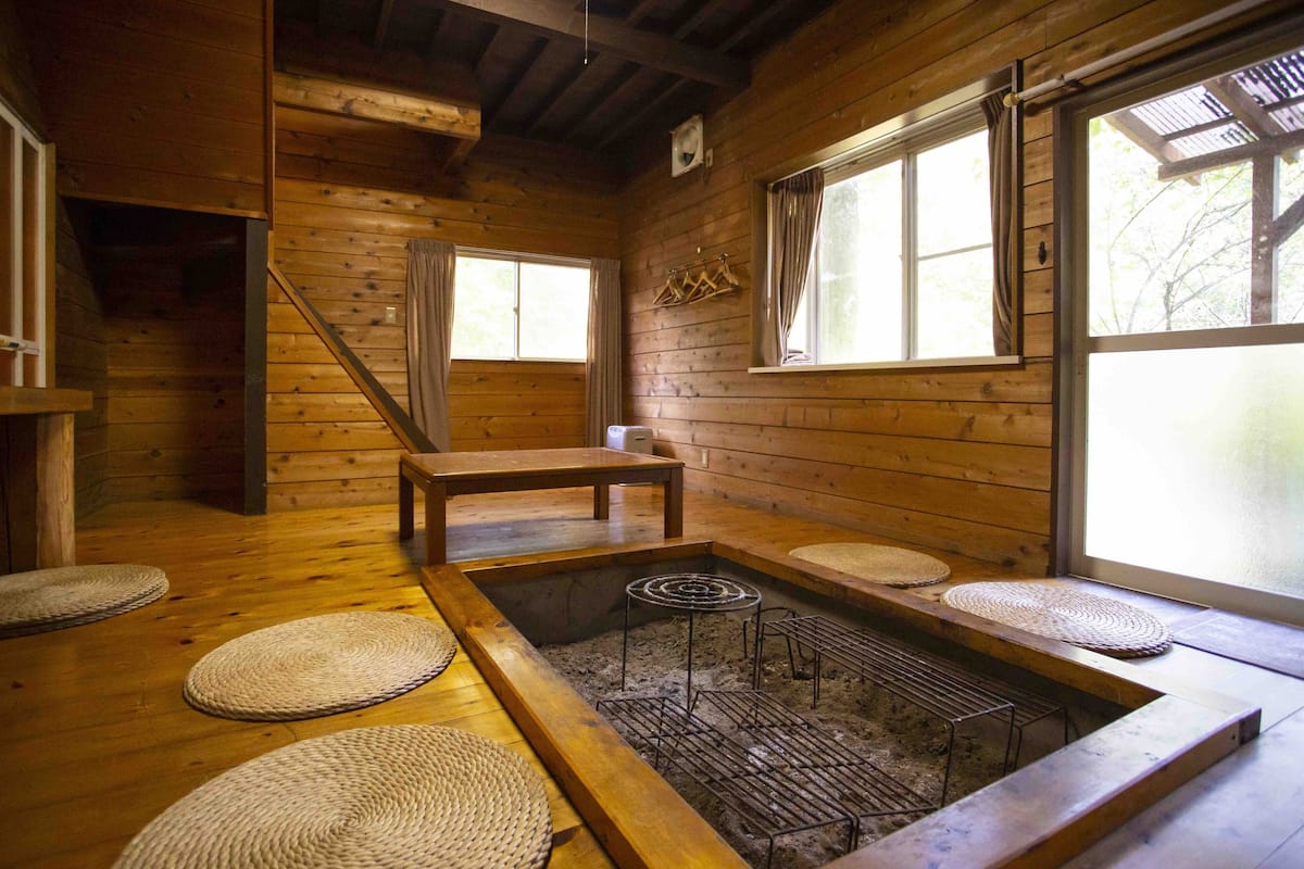 A wooden interior with a tatami mat room, a hot spring bath, and a window with curtains.