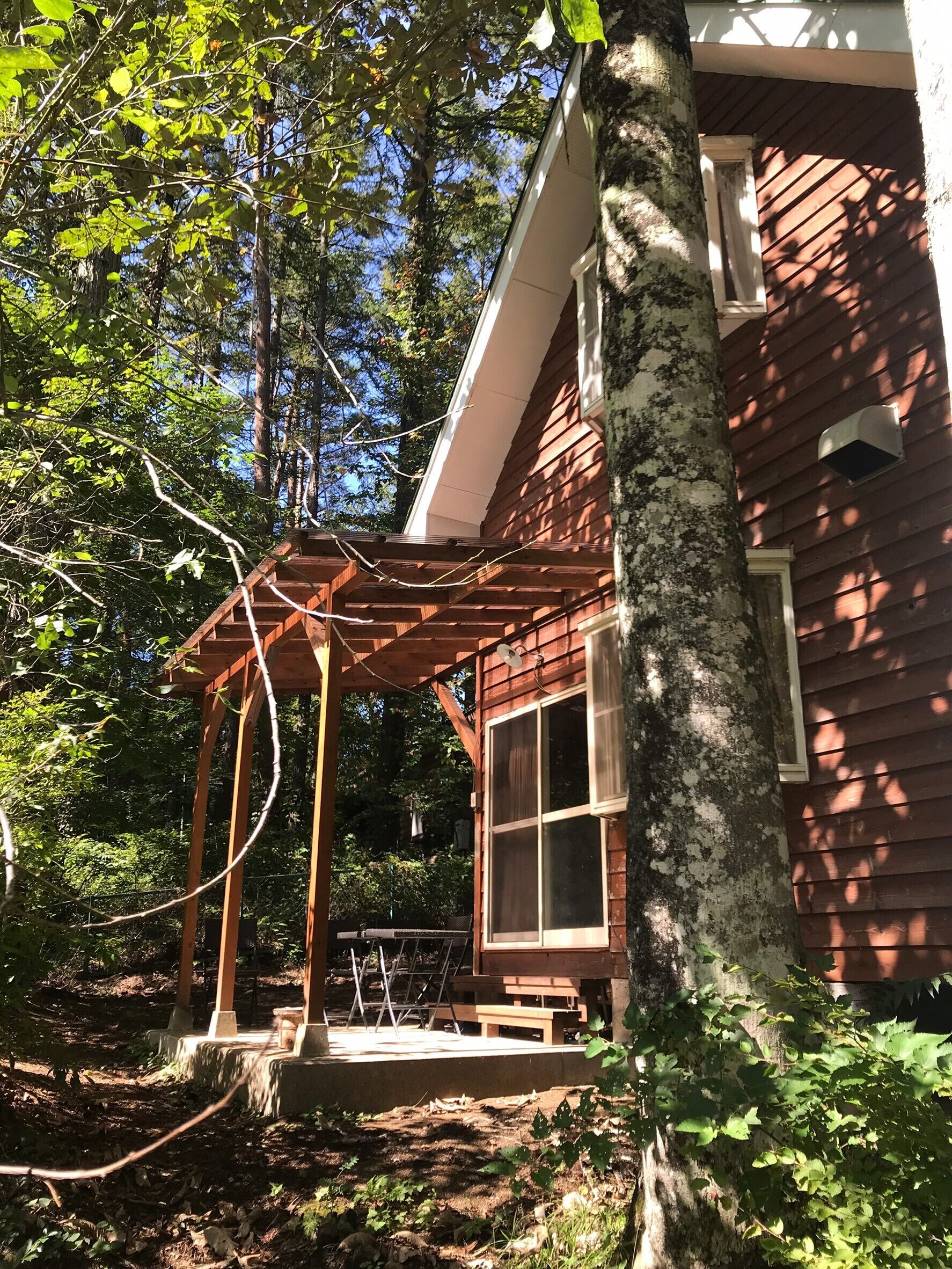 A wooden cabin with a covered porch, a window, and a small outdoor seating area.